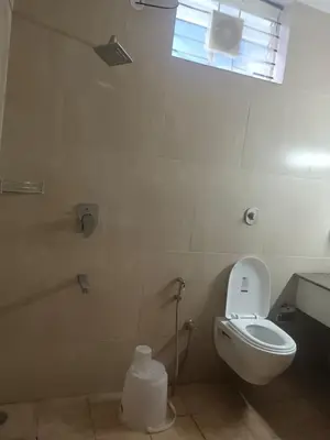 a bathroom with a toilet and a sink and a window at Coorg Nisrga residency near bus stand in Kushālnagar