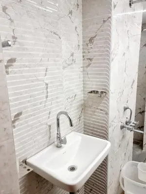 a white sink in a bathroom with white brick walls at Woods inn in Coimbatore
