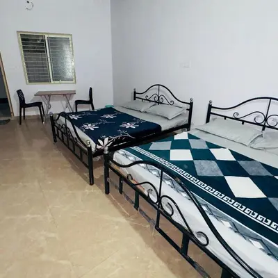 two beds in a room with a table and chairs at StayIn-SGH near Mysore palace in Mysore
