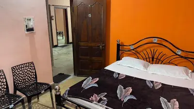a bedroom with a bed and a chair and an orange wall at StayIn-SGH near Mysore palace in Mysore
