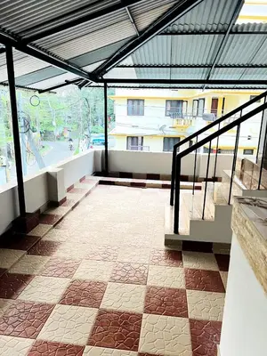 a building with a roof with a patio with stairs at Homestay Guruvayur, 1 AC & 1 Non AC bedroom in Guruvāyūr