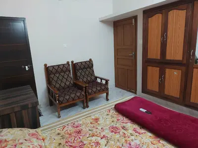 a bedroom with a bed and a chair and a rug at Homestay Guruvayur, 1 AC & 1 Non AC bedroom in Guruvāyūr
