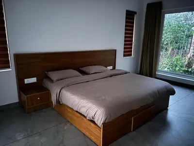 a bed in a bedroom with a large window at Thoniyot Heritage villas in Kalpetta