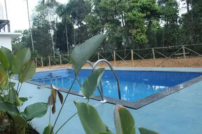 an empty swimming pool with a fence in the background at Thoniyot Heritage villas in Kalpetta