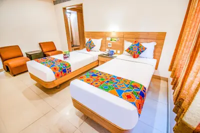 a hotel room with two beds and a chair at FabHotel Prime Royal Castle - Nr Coimbatore North Railway Station in Coimbatore