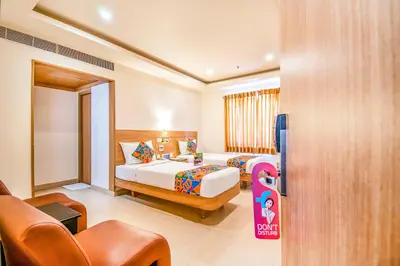 a hotel room with two beds and a couch at FabHotel Prime Royal Castle - Nr Coimbatore North Railway Station in Coimbatore
