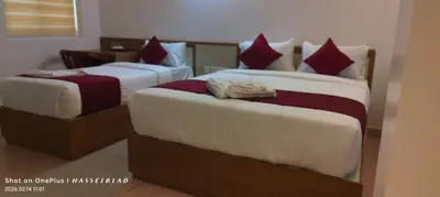 two beds in a hotel room with red pillows at Hotel Eden Palace in Trichūr