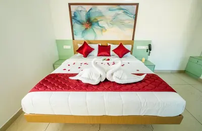 a bedroom with a large bed with two swans laying on it at Hotel Eden Palace in Trichūr