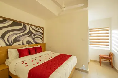 a bedroom with a bed with red pillows and a painting at Hotel Eden Palace in Trichūr