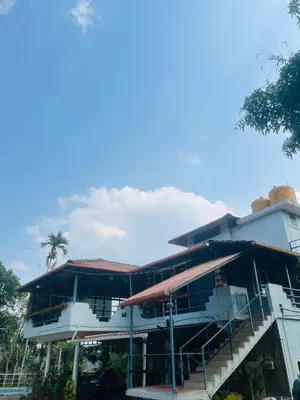 a large building with a staircase in front of it at Coorg Sana Riverside in Suntikoppa