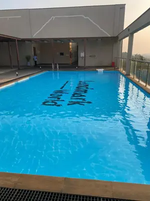 a large swimming pool with blue water at Landmark world Abacus 3P in Kakkayam