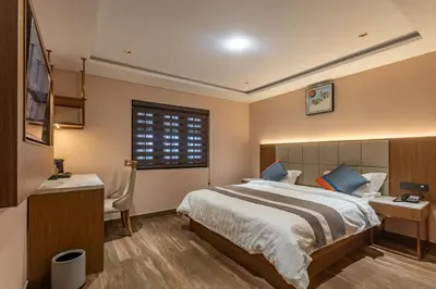 a bedroom with a bed and a desk and a window at Serenity Suites in Ooty
