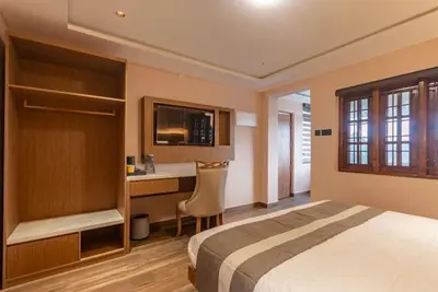 a hotel room with a bed and a desk at Serenity Suites in Ooty