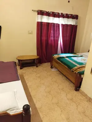 a bedroom with a bed and a window with red curtains at NKF Residency mysuru in Mysore