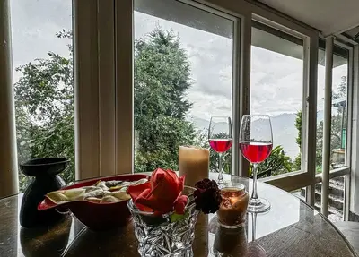 a table with two glasses of wine and a candle at Manas Valley View bungalow by Xacro Xperiences in Kodaikānāl