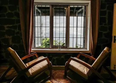 two chairs sitting in front of a window at Manas Valley View bungalow by Xacro Xperiences in Kodaikānāl
