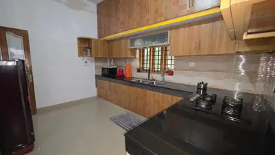 a kitchen with wooden cabinets and a black counter top at Serahs Homestay in Agali
