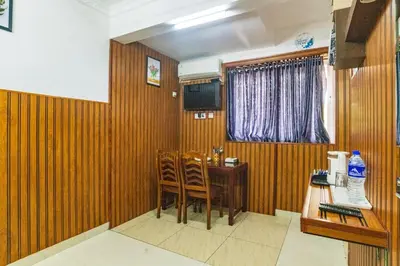 a dining room with wooden walls and a table and chairs at Blue Bell Hotel in Nedumbassery