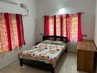 a small bed in a room with red curtains at Safari Homestay, Malayattoor in Kodanad