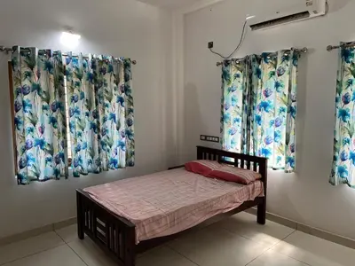 a small bedroom with curtains and a small bed at Safari Homestay, Malayattoor in Kodanad