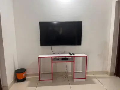 a flat screen tv sitting on top of a red table at Safari Homestay, Malayattoor in Kodanad