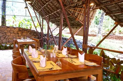 a wooden table with napkins on it in a restaurant at Toroland Munnar in Viripara