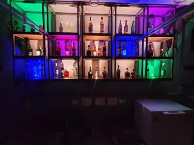 a shelf full of bottles in a dark room at Hotel Chithrapuri in Parli
