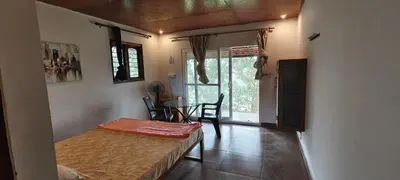 a room with a bed and a table and a window at wild grove resorts in Varagampadi