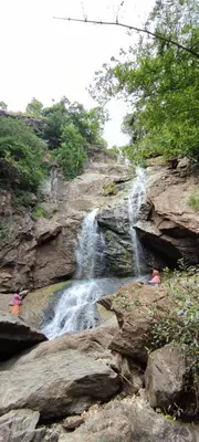 a waterfall on the side of a rocky mountain at wild grove resorts in Varagampadi