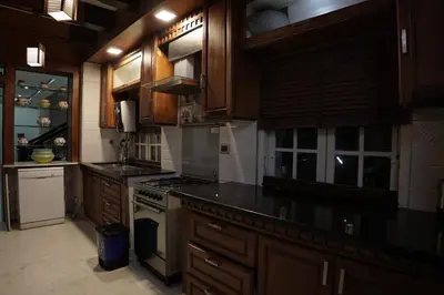 a kitchen with wooden cabinets and a stove top oven at Palamattam Villa Homestay,Angamaly, Kochi, Airport in Cochin