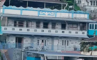 a man stands on the balcony of a building at River View Homestsy in Vālpārai