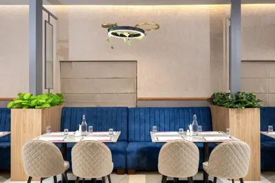 a restaurant with two tables and a blue couch at Nexstay Time Square in Kozhikode