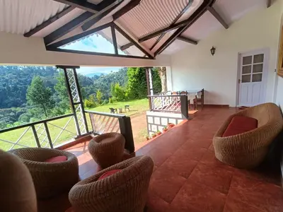 a living room with chairs and a large window at Jungle view in Coonoor