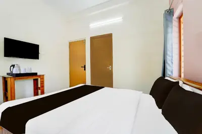 a bedroom with a white bed and a television at Super Collection O Westhill Near Govt Engg College in Calicut