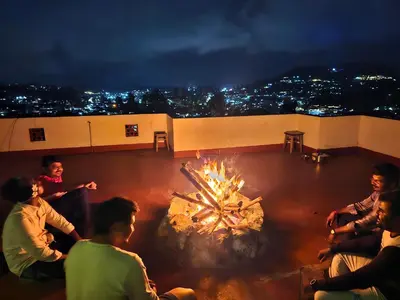 a group of people sitting around a fire pit at Mellowlux Ooty in Ooty