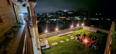 a group of people sitting around a table on a balcony at night at Mellowlux Ooty in Ooty