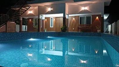 a swimming pool in front of a house at night at Captain's Castle in Pallipuram