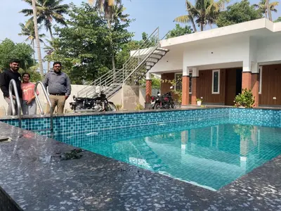 a group of people standing next to a swimming pool at Captain's Castle in Pallipuram