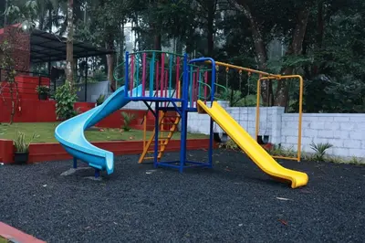 a playground with a blue and yellow slide at Blizzard Pool Villa in Padinjarathara