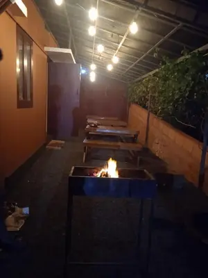 a room with a fire pit with benches in it at Blizzard Pool Villa in Padinjarathara