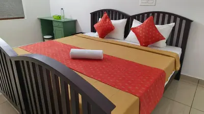 a bed with red pillows and a red blanket at Ashirvad Homes in Mannārakkāt