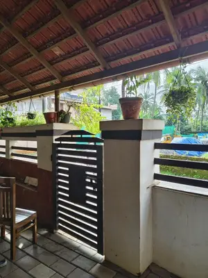 a patio with a gate with a table and a chair at Ashirvad Homes in Mannārakkāt