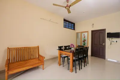 a dining room with a table and chairs and a bench at sky blue villa in Vythiri