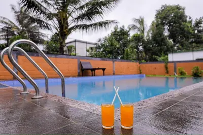 two drinks on a table next to a swimming pool at sky blue villa in Vythiri