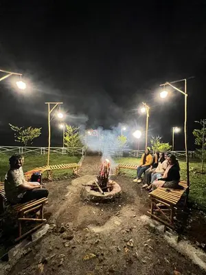 a group of people sitting around a fire at night at Wildglamps Athirappilly in Athirappilly