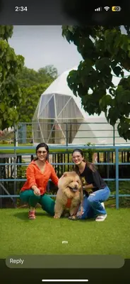 three women sitting on the grass with a dog at Wildglamps Athirappilly in Athirappilly