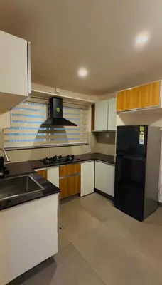 a kitchen with a black refrigerator and white cabinets at AJ Wayanad Suites in Kalpetta