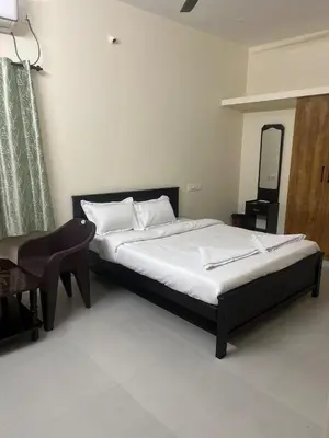 a bedroom with a bed and a chair and a mirror at Subam Residency in Singānallūr