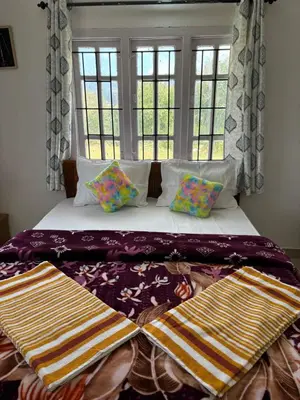 a bedroom with a bed with pillows and a window at Crown Crest in Ooty