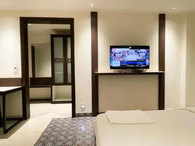 a room with a bed and a television on a wall at SV Grand in Mettuppālaiyam